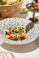 Traditional italian food - panzanella salad with tomatoes, onion rings and croutons. Panzanella salad on white table in summer menu. Composition with Tomato salad and glasses in sunny day.