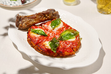 Traditional italian dish - milanese steak in breaded and parmesan on white ceramic plate. Milanese...