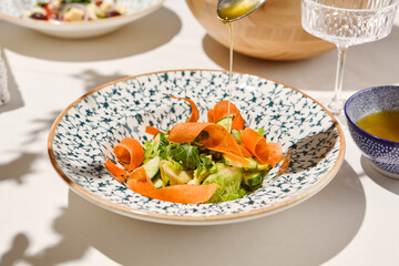 Healthy food - vegetable salad with cucumber and carrot in ceramic bowl on sunny day. Vegetarian salad with greens and vegetables. Vegan food. Vegan menu. Rustic Green salad with carrot and cucumber.