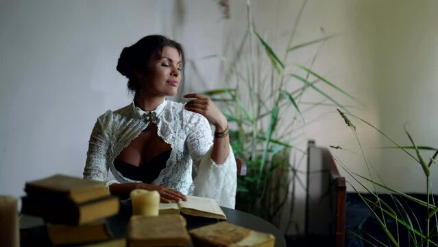charming brunette woman is reading books in room with romantic and historical atmosphere