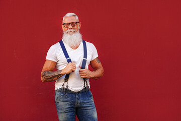 Portrait of casual, confident senior with long white beard and mustache and tattoos . Man wearing...