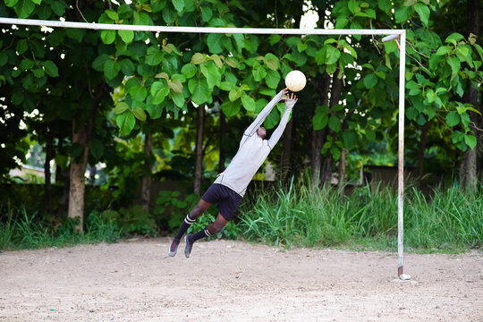 African Goalkeeper Catching Football In Goalpost On Field - Black Goalie Defending Penalty Kick In Competition