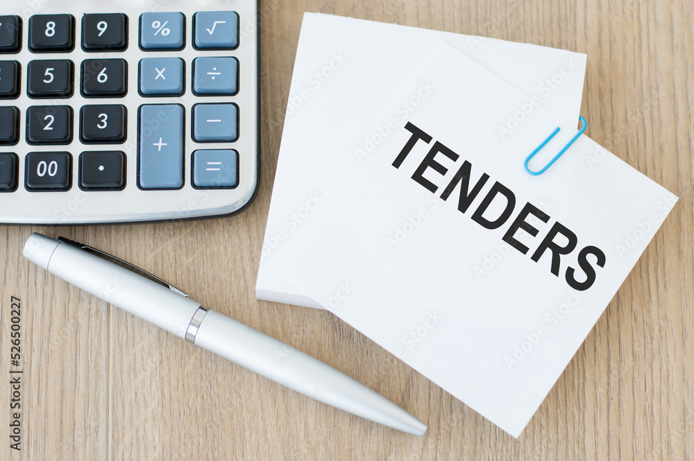 Poster invitation for tender text on a card that is on a paper clip to a stack of notes sheets on a wooden 