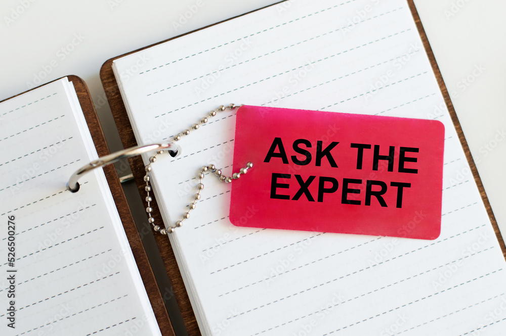 Poster ask our expert text on a red card that sits on an open notebook on the table