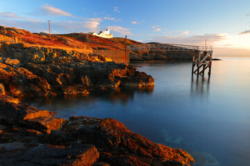 Obraz premium Point Lynas Lighthouse at first light with calm blue sea. Anglesey, North Wales, UK.