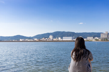 夏の海岸で海を眺める女子の後ろ姿