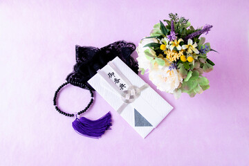 お供えの花とお香典と数珠と黒いレースのハンカチーフ（紫色の背景）