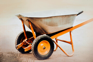 A garden metal wheelbarrow for transporting grass and other materials stands empty in the yard....