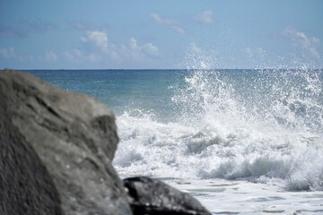Fototapeta premium Ocean waves crashing on sandy beach. Sea waves breaking on shore. Nature splash on summer day. Sea wave crashing on beach. Coastal storm and storm weather concept. Splashing sea water with foam.