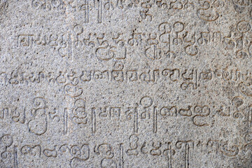 Inscriptions of tamil text on the walls of historical ancient temple in Tamilnadu. Ancient tamil inscriptions carved in the exterior temple walls. Stone wall texture.