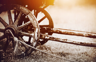 An old retro wooden cart with big wheels stands in a field, illuminated by sunlight. Transport of...