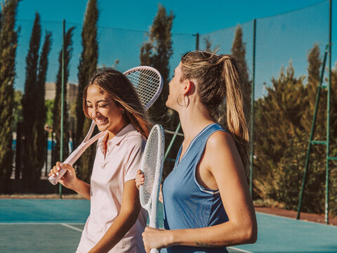 Amigas felices jugando al tenis al aire libre durante el verano
