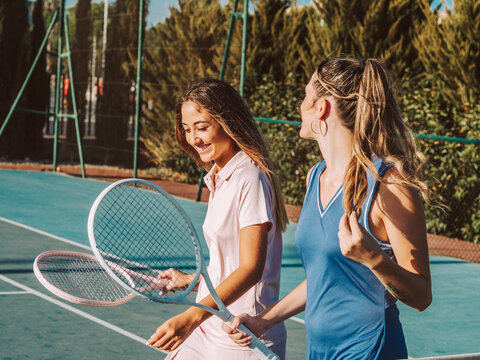 Amigas felices jugando al tenis al aire libre durante el verano