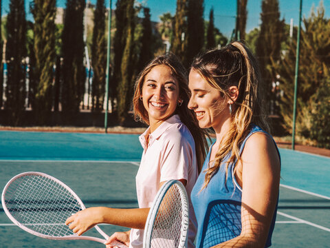 Amigas felices jugando al tenis al aire libre durante el verano