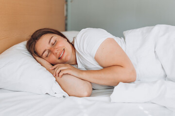 Obraz na płótnie Canvas Young beautiful woman sleeping in bed at home. Millennial Caucasian girl sleeping on soft pillow, enjoying sweet dreams good night rest in bed. Photo of sleeping woman lies in bed with eyes closed.