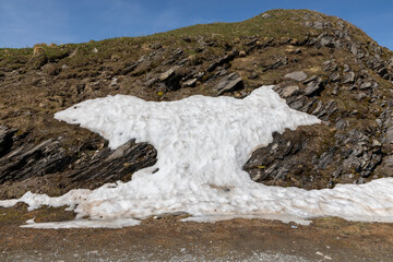 Melting snow on the side of a rock face in springtime in Switzerland. 