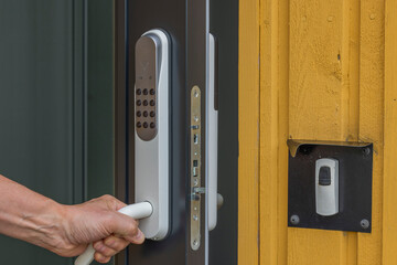 View of man's hand opening entrance door with digital lock. Sweden.