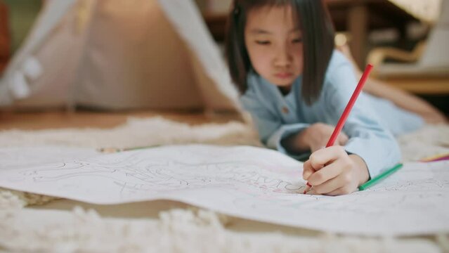 Asian Little Artist Drawing with her Favorite Orange Crayons on a Blank Paper Book, a Creative Baby Girl Showing her Imagination via Artwork on Floor While Stays at Home, Creative Practicing