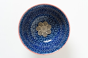wooden ornament at the bottom of a blue bowl with curly pattern