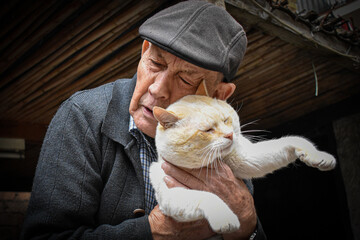Hombre mayor con gorra abrazando a su gato blanco