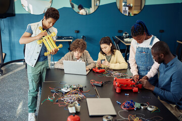 Diverse group of teenage kids building robots together while enjoying engineering class in modern school