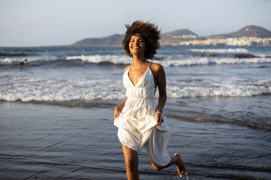 Beautiful young black african girl running happily on the beach.