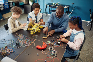 High angle view at diverse group of kids building robots during engineering class at school with...