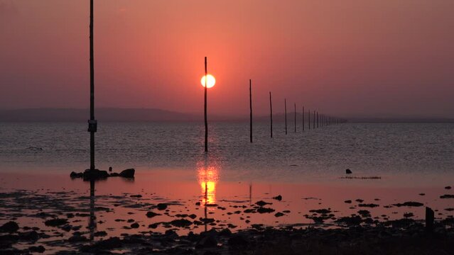 Sunset over sand on Lindisfarne holy island relaxing and meditation in nature. Northumberland seaside with sun going down over water in evening UK 4K