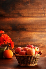 closeup wicker basket with gala apples and pumpkin on rustic wood 