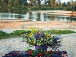 Still life with bouquet of wildflowers on a river bank