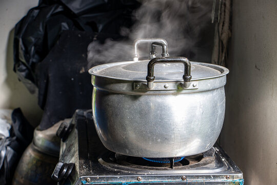 Steam rises from the aluminum pot on the stove