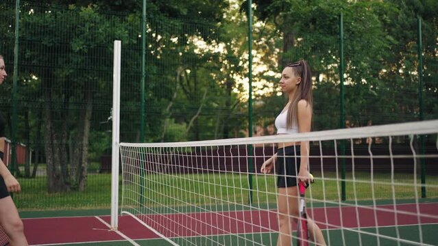 two female tennis player are welcoming each other on court, shaking hands and going to place