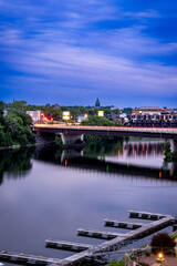 Fototapeta na wymiar Schenectady, NY - USA - Aug 1, 2022 vertical view during the blue hour of Schenectady’s skyline, with the Freemans Road Bridge and the Mohawk River in the foreground