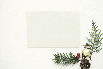 Christmas card mock up. Empty greeting card flat lay with fir branches, berries and christmas decorations on rustic white table. Postcard template with space for text. Happy Holidays!