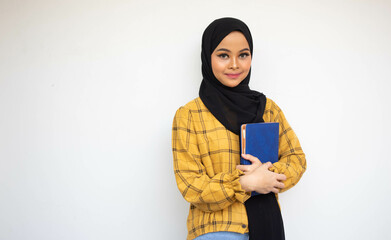 Beautiful veiled student carrying books with smile looking the camera at isolated background
