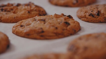 Close-up shot of freshly baked chocolate chip cookies on white table, slow motion