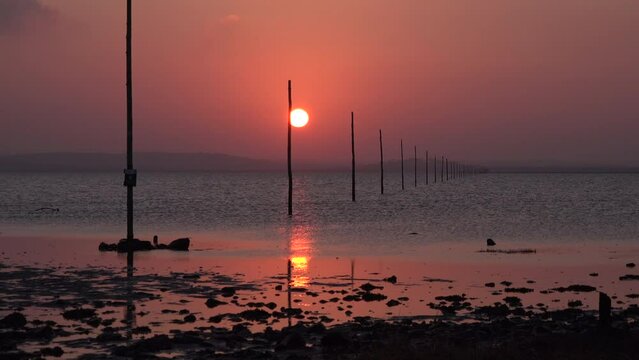 Sunset over sand on Lindisfarne holy island relaxing and meditation in nature. Northumberland seaside with sun going down over water in evening UK 4K