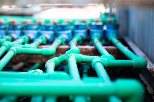 Selective focus to many PPR green water pipe with blurry water meter and valve.