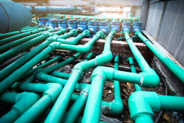 Selective focus to many PPR green water pipe with blurry water meter and valve.