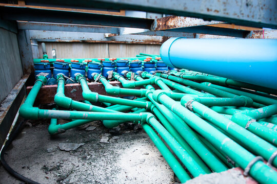 Selective focus to many PPR green water pipe with blurry water meter and valve.