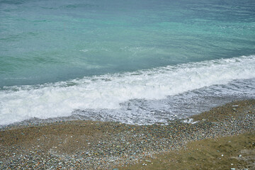 Sea shore with pebbles, wet sea pebbles on the beach and quiet sea surf. Restless sea and waves