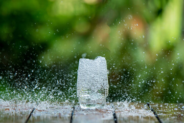 Clear water tornado, whirlwind and splash around the glass of water placed on the wooden bar....