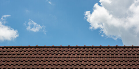 Naklejka premium Old red roof tiles on blue sky with clouds background.
