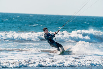 young latino practicing kitesurfing in the pacific ocean