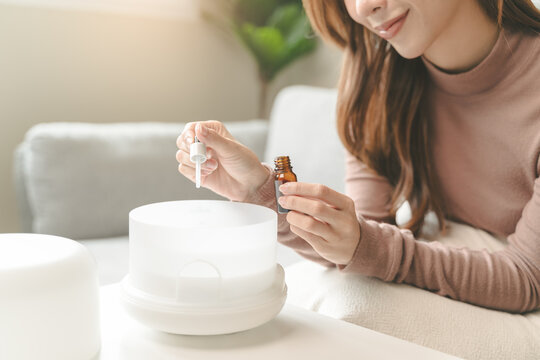Women drop essential oil into the humidifier to make aromatherapy refreshments atmosphere house for relaxation.