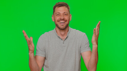 Fototapeta premium Happy handsome young man shouting, raising fists in gesture I did it, celebrating success, winning, birthday, lottery goal achievemen. Adult guy isolated on green chroma key studio background indoors