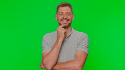Portrait of happy bearded handsome young man in gray t-shirt looking at camera, smiling. Adult stylish male guy isolated alone on green screen chroma key studio background indoors. Male nature beauty