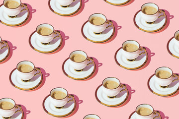 Vintage porcelain coffee cups and saucers, creative bright pattern on pastel pink background. Retro style café  idea. 