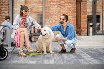 Stylish man and woman care adorable white dog while hanging out together at cafe terrace. Man...