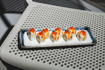 Sushi rolls with eel, shrimp, cucumber and cream cheese, decorated with red caviar. Hard light, deep shadow